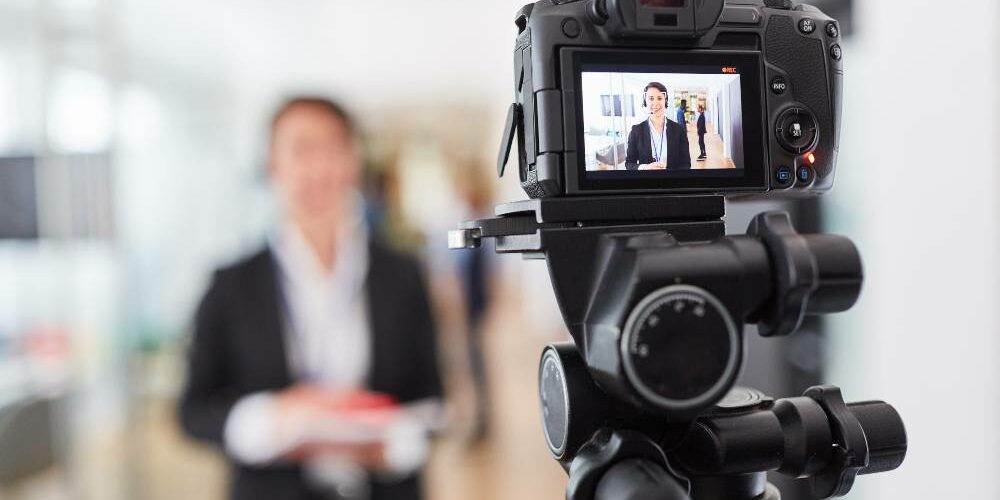 Video camera recording a business woman for an online tutorial